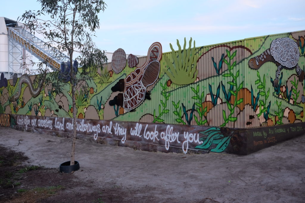 Photo of mural painted on fence beside bike path alonhg the Maribyrnong River. Words: Look after our ancestors land and waterways and they will look after you