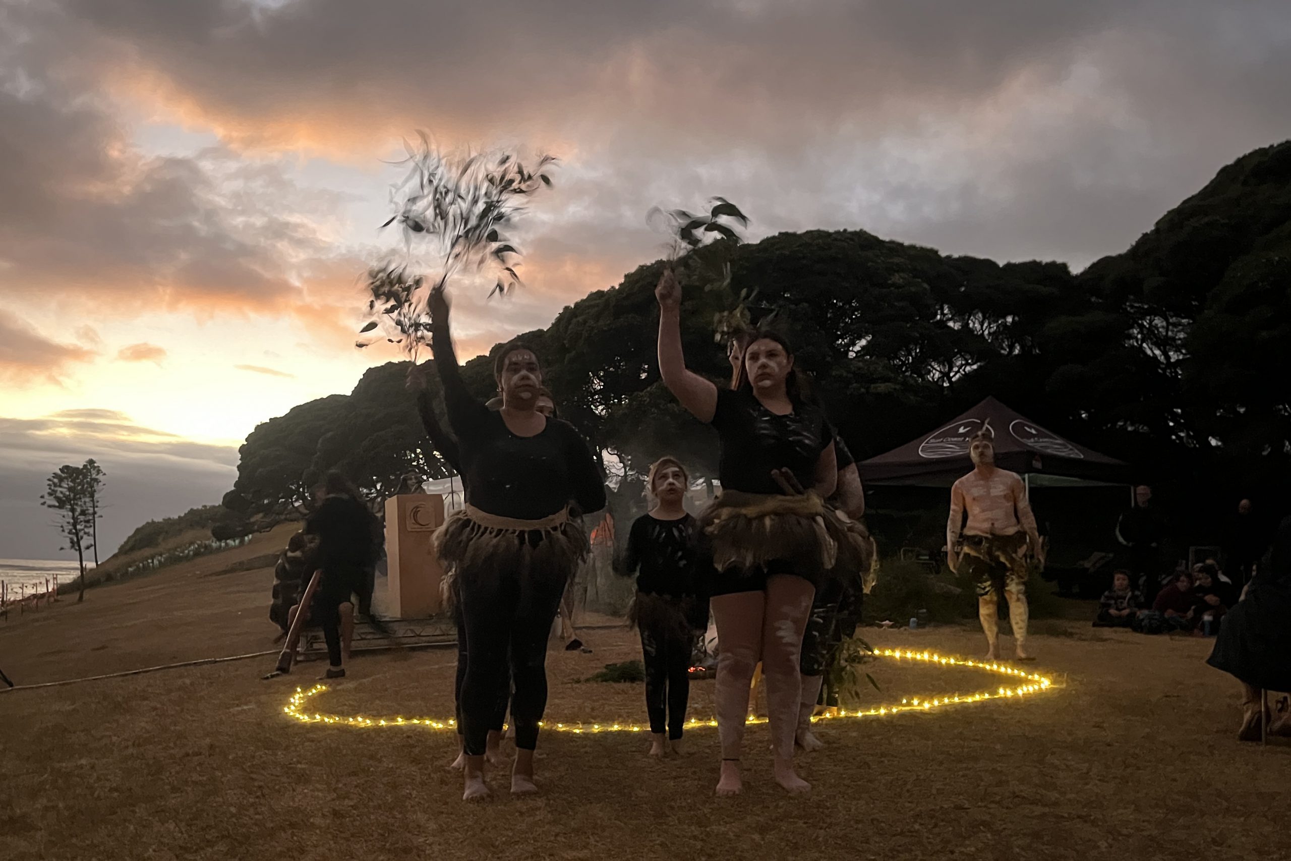 Photo of dancers at sunrise standing around a circle of candles