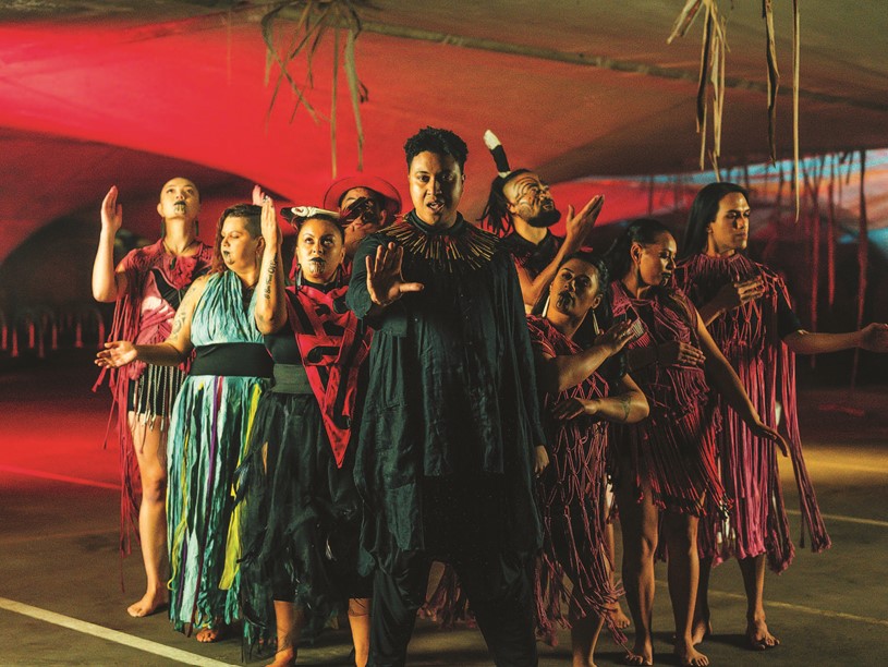 9 Indigenous people in costume pointing their hands
