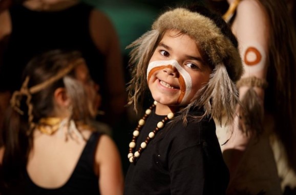 Image of child with painted face and aboriginal traditional costume smiling