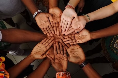 Several hands coming together in a circle palms facing up