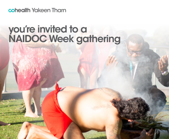 Smoking ceremony with aboriginal man in traditional dress blowing on the smoke as someone in leaning in to receive the smoke