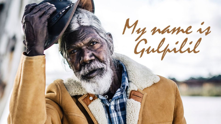 Image of and Aboriginal Man, David Gulpilil tipping his hat and wearing a sheepskin jacket