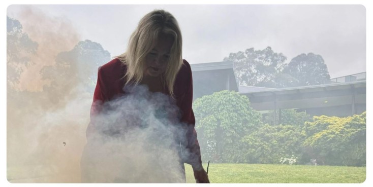 Image of Jillian West, Aboriginal behind smoke from ceremony with nature in the background