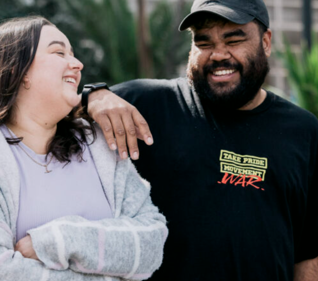 Image of 2 people. Person on the righ has his hand on the shoulder of the person on the left.